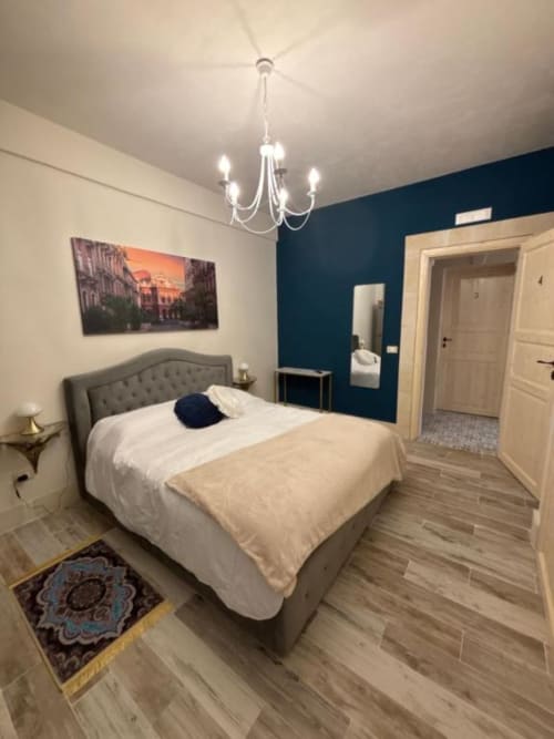 Camera da letto doppia moderna a Villa Brikinnia a Lentini con parete teal, elegante lampadario e vista giardino