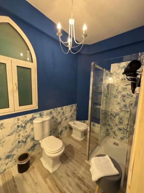 Bagno moderno di Villa Brikinnia con pareti blu navy, sanitari bianchi, cabina doccia e dettagli decorativi in piastrelle blu