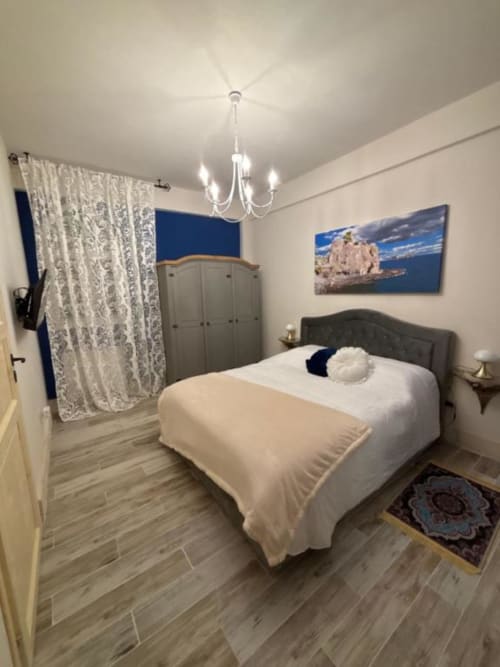 Camera matrimoniale n. 4 a Villa Brikinnia a Lentini con letto queen, testata grigia, lampadario e quadri con soggetti marini