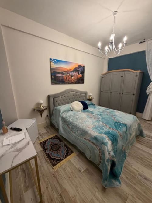 Camera matrimoniale moderna a Villa Brikinnia a Lentini con letto imbottito, armadio, lampadario e opere d'arte. Giardino