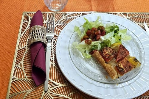 Plated dish at Aux Prés Du Berry with seared meat, fresh greens, and garnish on elegant white plate