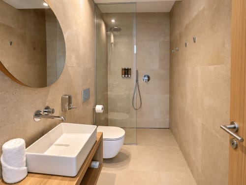 Baño moderno en apartamento de Baiona con ducha tipo walk-in, lavabo tipo vaso, inodoro y toallero climatizado