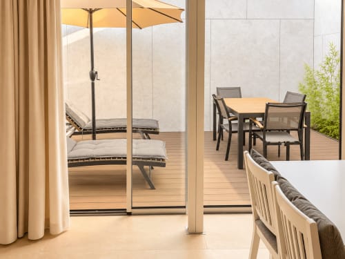 Amplia terraza del apartamento Holibai Baiona con mesa de comedor, tumbonas, sombrilla amarilla y vistas al mar