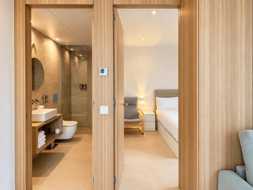 Pasillo moderno del apartamento Holibai en Baiona con puertas abiertas al baño y dormitorio con marcos de madera y calidez