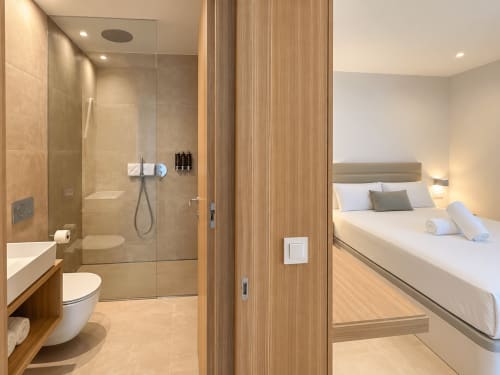 Moderno cuarto de baño y dormitorio en el apartamento ModulSenses de Holibai, Baiona con ducha, inodoro y cama