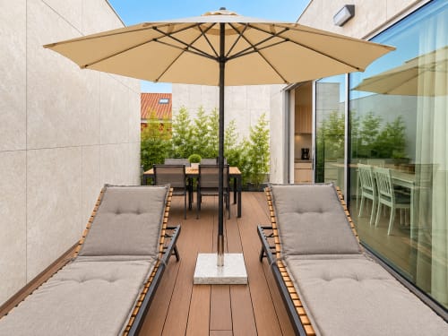 Terraza moderna del apartamento Holibai en Baiona con tumbonas, sombrilla, zona de comedor y vistas al jardín