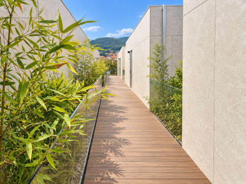 Terraza de madera moderna en el apartamento Holibai de Baiona con plantas de bambú, vistas a la ciudad y fondo de montañas