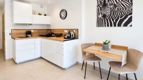 Cuisine studio moderne avec plan de travail en bois, meubles blancs, table et chaises à Le 9 Victor Hugo, Aix-les-Bains