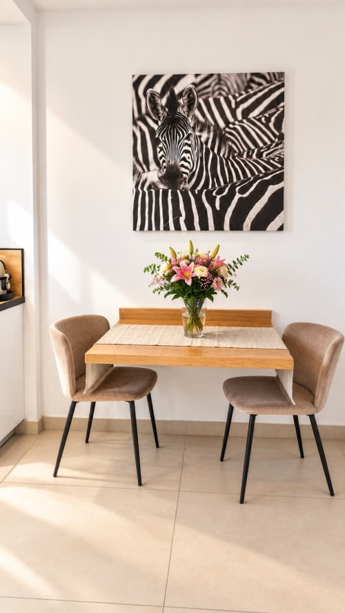 Studio moderne au 9 Victor Hugo : table en bois, chaises rembourrées, fleurs roses et art zébré