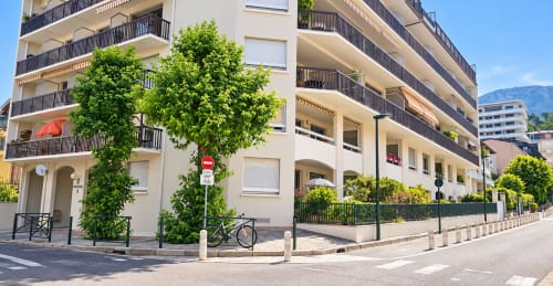 Immeuble Le 9 Victor Hugo à Aix-les-Bains avec lierre verdoyant, balcons et vue de rue par beau temps