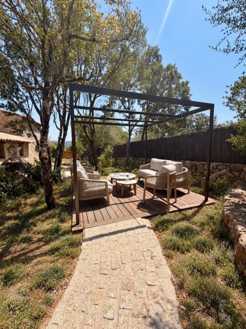 Espace lounge en pergola extérieure aux Villas d'A Storia, Porto-Vecchio, avec sièges, table et arbres matures