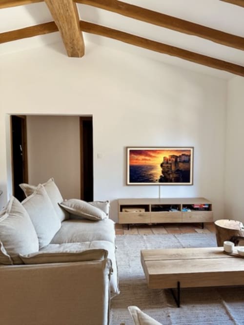 Salon moderne de villa avec canapé blanc, poutres en bois, téléviseur écran plat et tableau coucher de soleil aux Villas d'A Storia