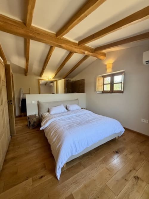 Chambre rustique avec plafond à poutres apparentes aux Villas d'A Storia à Porto-Vecchio, literie bleue et fenêtre