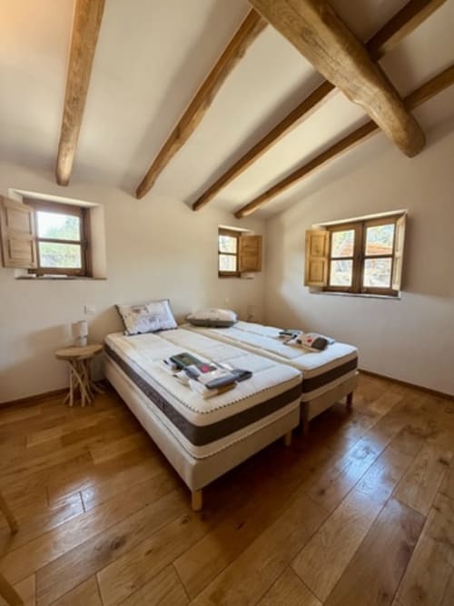 Chambre spacieuse aux poutres apparentes des Villas d'A Storia à Porto-Vecchio, avec lits jumeaux et boiseries