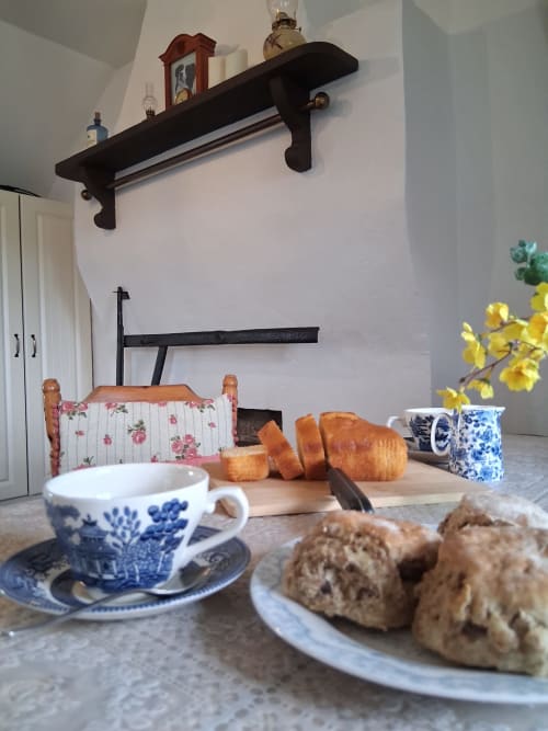 Cozy cottage dining setup at Ballymultimber in Limavady with blue and white teacup, fresh bread, and scones at table near