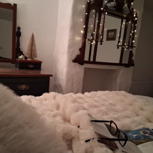 Cozy bedroom at Cissy's Cottage in Limavady with white bedding, wooden furniture, mirrors with fairy lights, and festive