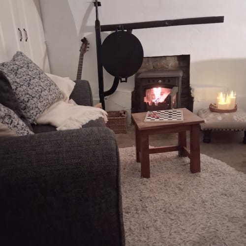 Cozy sitting area at Cissy's Cottage, Limavady, with fireplace, guitar, and chessboard by warm fire