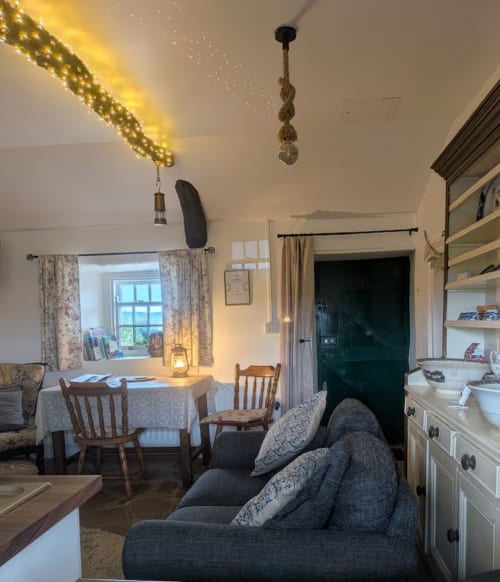 Cozy sitting area in Cissy's Cottage at Ballymultimber, Limavady, with dining table, armchair, and holiday decorations