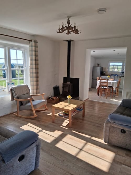 Spacious living room at Ballymultimber Cottages in Limavady with wood stove, comfortable seating, and mountain views through