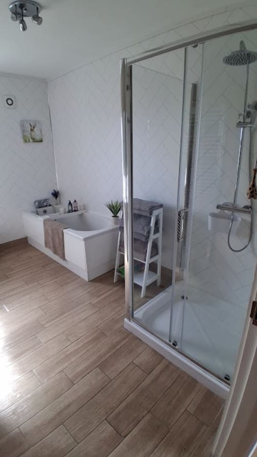Modern bathroom at Ballymultimber Cottages with walk-in shower, soaking tub, and wood-style flooring in Limavady cottage
