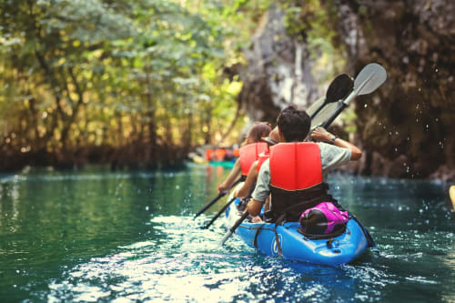 Kayakers paddling through turquoise water surrounded by lush cliffs near Fontcouverte, France at Domaine Le Piboul.