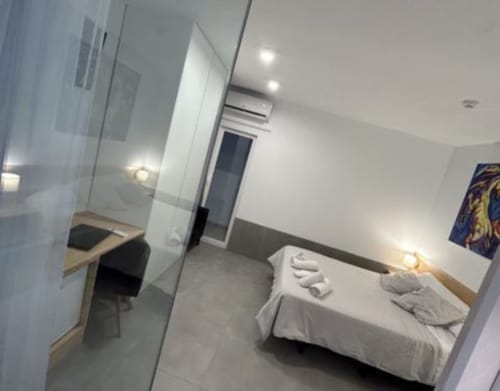 Habitación moderna en Hostal Fornet Altea con cama, escritorio y decoración minimalista en blanco