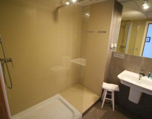 Baño moderno en Hostal Fornet Altea con ducha a ras de suelo, lavabo pedestal y azulejos en tono beige en Altea, España