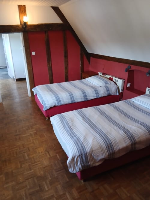 Chambre mansardée de la maison d'hôtes Chez Robins à Trie-Château : murs rouges, poutres en bois, literie rayée