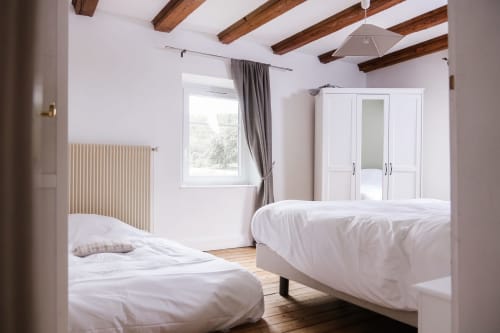 Chambre lumineuse au gîte La Maison du Gardien des Cabanes du Nideck avec lits jumeaux, poutres apparentes, armoire blanche et