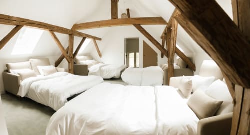 Chambre spacieuse des Cabanes du Nideck avec poutres apparentes, literie blanche et plusieurs lits à Oberhaslach.