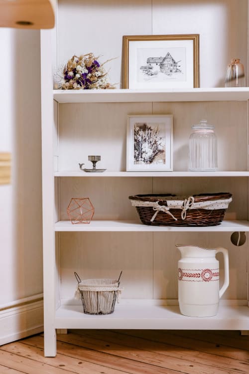 Étagère en bois rustique aux Cabanes du Nideck garnie d'objets de décoration, tableaux encadrés, paniers et objets vintage