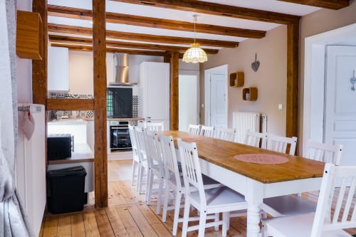 Salle à manger avec poutres en bois, chaises blanches et table en bois à La Maison du Gardien, Les Cabanes du Nideck