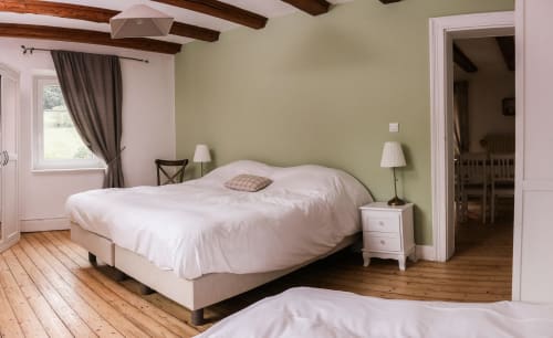 Chambre lumineuse à La Maison du Gardien des Cabanes du Nideck avec lit queen-size, poutres en bois et vue sur les montagnes