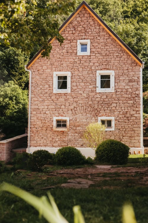 Red brick cottage La Maison du Gardien at Les Cabanes du Nideck, Oberhaslach, surrounded by lush greenery