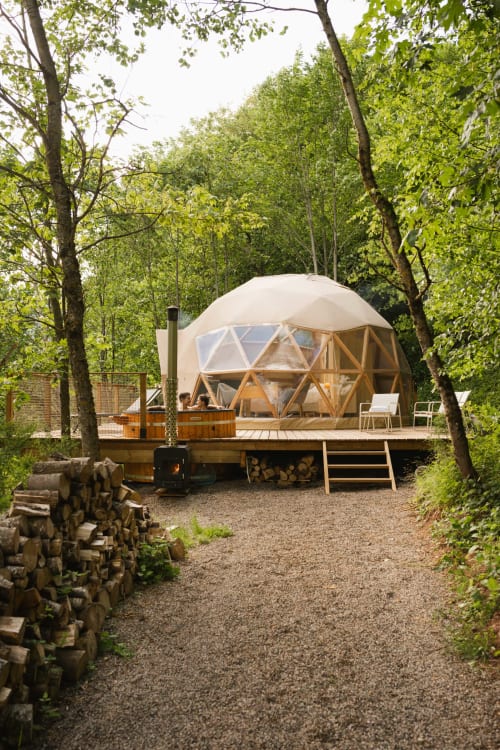 Geodesic dome cabin surrounded by green forest trees with hot tub and wooden deck at Les Cabanes du Nideck in Oberhaslach,