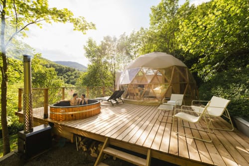 Dôme géodésique aux Cabanes du Nideck avec bain à remous en bois, chaises longues et vue sur la forêt vosgienne en Alsace