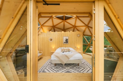 Chambre sous dôme géodésique aux Cabanes du Nideck : lit blanc, intérieur bois et vue montagne