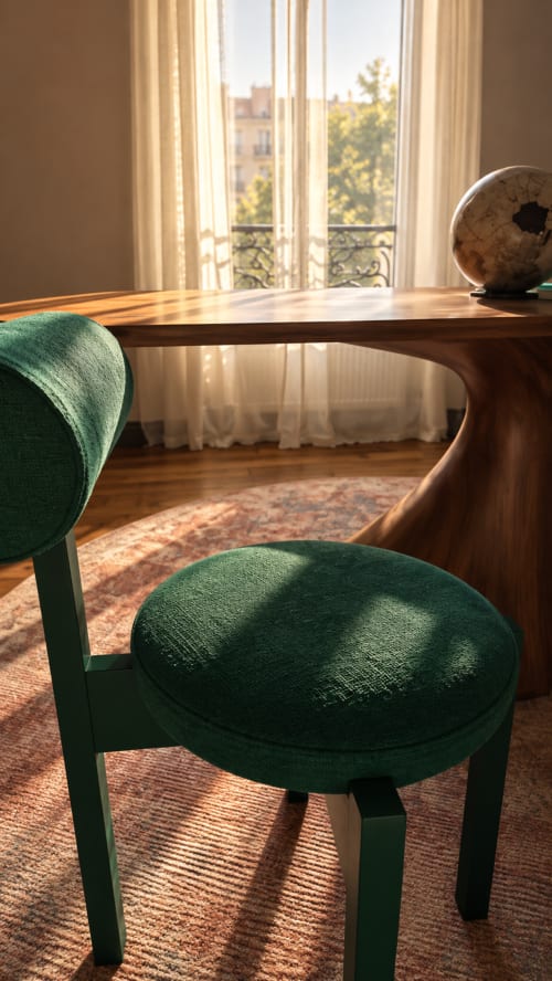 Espace de travail élégant à La Maison 1903 avec chaise verte, table en bois, globe et vue sur les rues de Paris par les rideaux