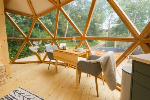 Intérieur de dôme géodésique moderne aux Cabanes du Nideck avec mobilier en bois, espace repas et vue sur la forêt