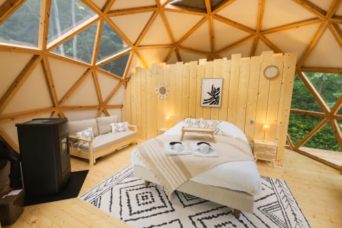 Chambre en dôme géodésique aux Cabanes du Nideck avec lit, canapé, intérieur bois et vue montagne par les lucarnes