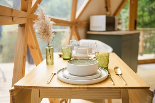 Table élégamment dressée au sein d'un dôme géodésique aux Cabanes du Nideck à Oberhaslach, avec assiettes blanches, verres verts, décor desséché