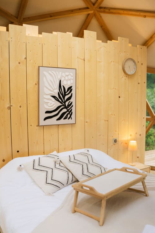 Chambre cosy en dôme de bois aux Cabanes du Nideck avec literie blanche, coussins géométriques, art botanique encadré et bois