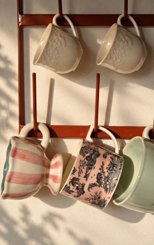 Tasses en céramique accrochées à une tringle rouge à La Maison 1903 B&B à Trévou-Tréguignec, France