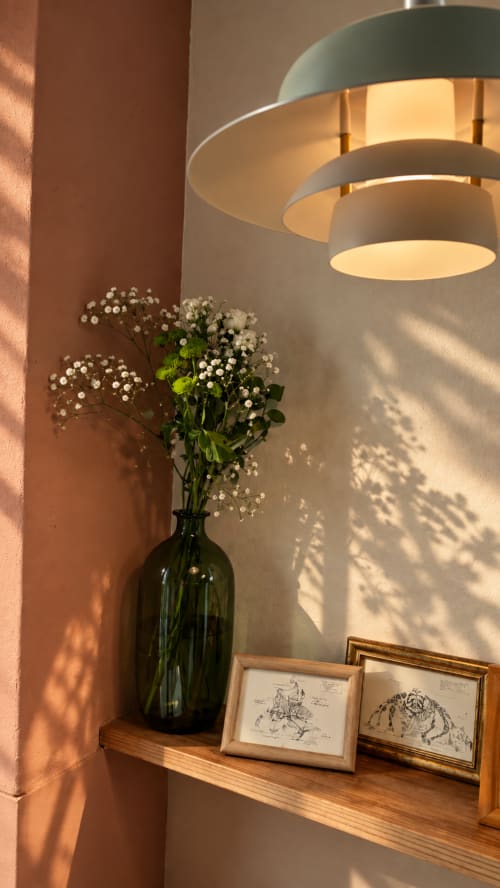 Élégant coin d'exposition à La Maison 1903 avec gypsophile blanche, luminaire suspendu moderne et esquisses botaniques encadrées