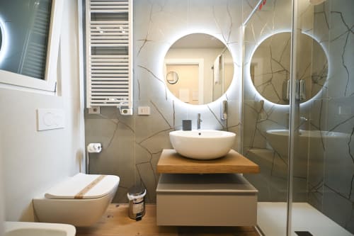 Modern bathroom at Vimini Apulian Experience in Bari with dual illuminated mirrors, vessel sink, wooden vanity, and walk-in