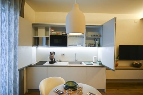 Modern kitchenette at Vimini Apulian Experience in Bari with white pendant light, dining table, and sea-view apartment