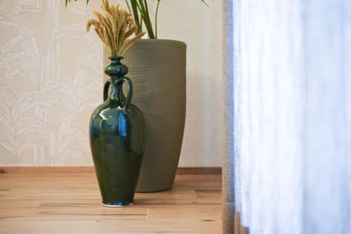 Dark green ceramic vase with dried grasses and textured taupe vase on wooden table at Vimini Apulian Experience, Bari