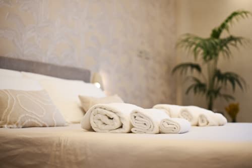 Rolled white towels on bed in Conchiglia apartment at Vimini Apulian Experience, Bari