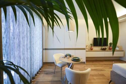Conchiglia apartment at Vimini Apulian Experience, Bari: modern living space with palm plants, blue curtains, wooden table,