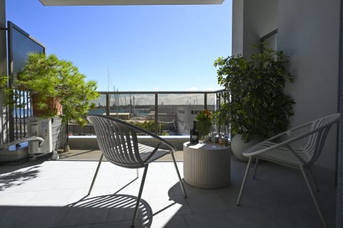 Modern rooftop terrace at Vimini Apulian Experience in Bari with contemporary seating, potted plants, and marina views